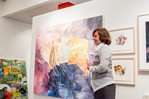 Mme Nicole Brière devant des œuvres de Mélanie Authier. Sur le mur du fond, à droite, un aperçu d'un tableau de Dan Brault. Crédit photo: Isabelle Houde Photographe