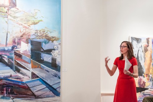 Andréanne Lesage - Historienne de l'art avec, à sa droite, un tableau de Martin Golland. À sa gauche, un aperçu d'une œuvre de Michael Smith. Crédit photo: Isabelle Houde Photographe